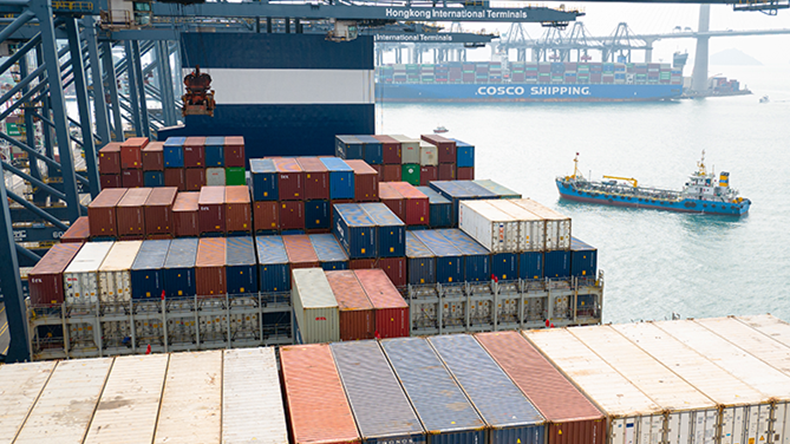 Container vessel with gantry crane at Hong Kong International Container terminal and small bunker ship approaching from side