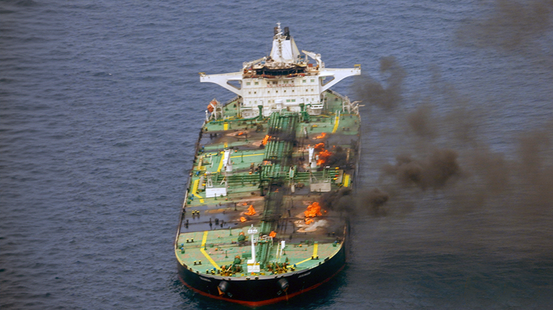 Oil tanker with hatches on fire and black smoke at sea