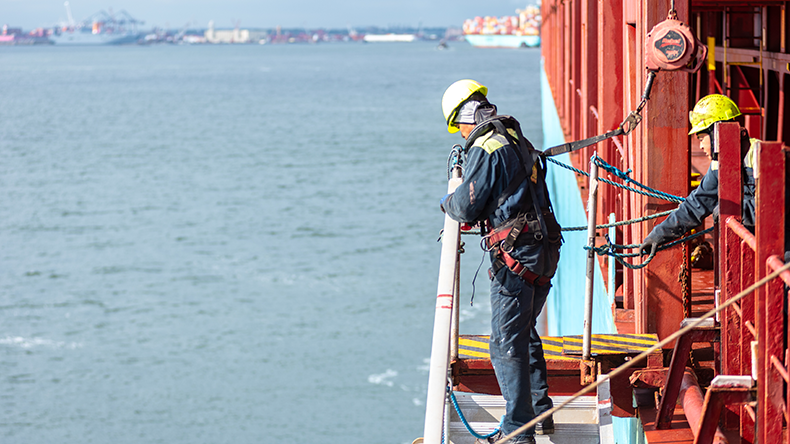 A deckhand prepares the pilot ladder as the ship readies for port entry