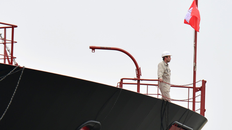 Seafarer looks out from prow of ship