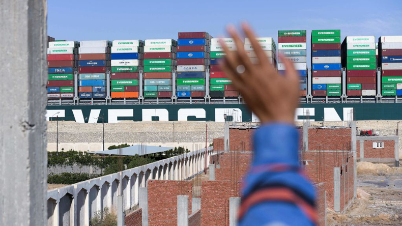 Man waving at Ever Given as it is tugs pull it clear to resume sailing. Credit: Ahmad Hassan / AFP via Getty Images