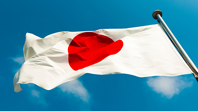 Japanese flag on the strong wind over blue sky background