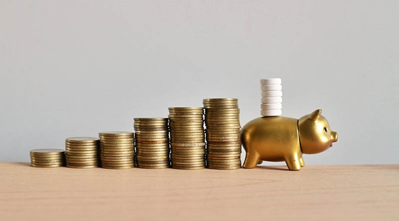 Gold piggy bank carry white pills and rolls ladder of coins money on wood table