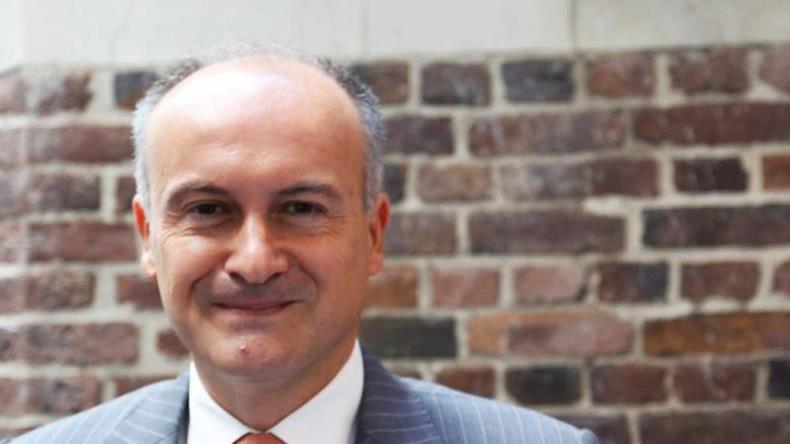 George Theocharidis head and shoulders shot in front of a brick wall