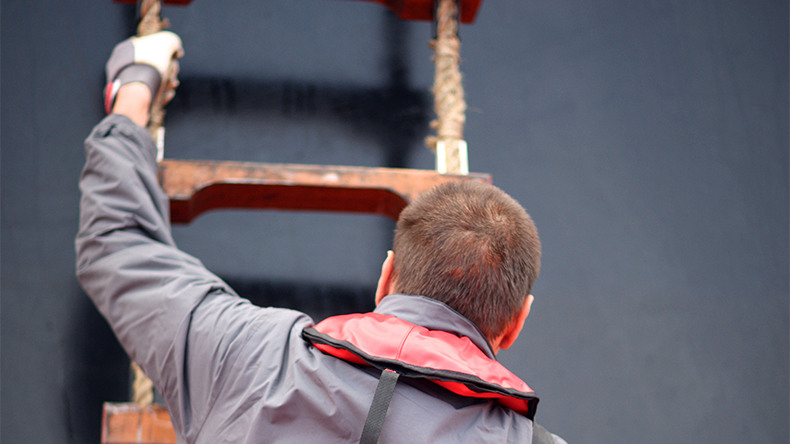 A man climbs the rope ladder to board a ship