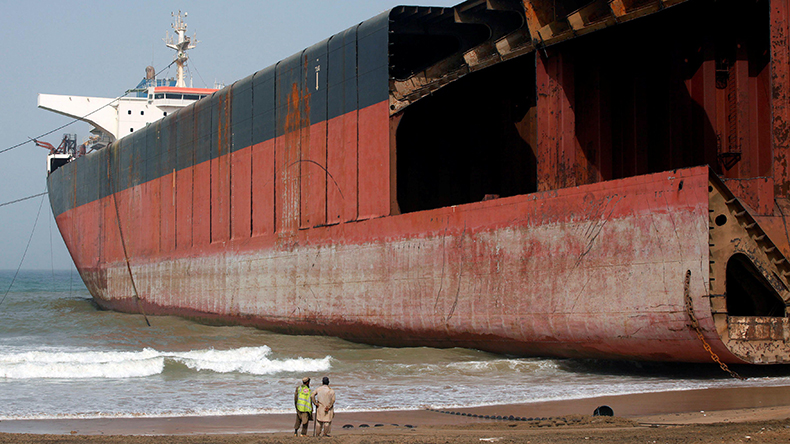 Labourers stand in front of a ship, part of which has been broken up for scrap metal, at shipbreaking yard in Gadani, Baluchistan province, Pakistan May 17, 2018. Picture taken May 17, 2018. REUTERS/Akhtar Soomro
