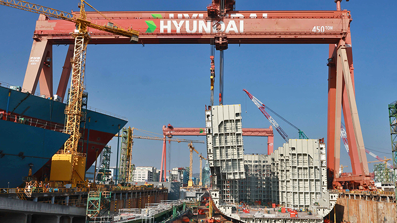 HD Hyundai Heavy Industries shipyard with blue sky and gantry crane