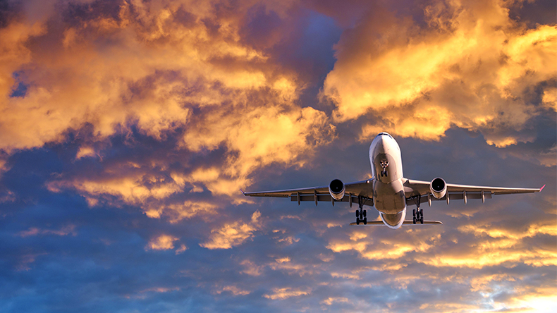 Passenger airplane is flying in colorful sky at sunset