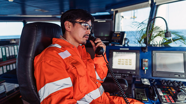 Filipino deck officer on bridge of ship. He is speaking on VHF radio
