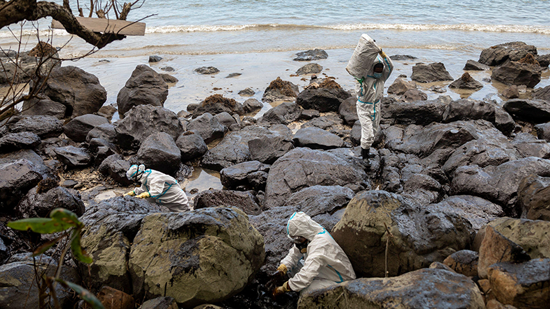 Volunteers dressed in PPE clean up the oil spill from the sunken tanker Princess Empress